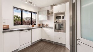 Una cocina moderna con armarios blancos, un refrigerador de acero inoxidable, un microondas y un horno.