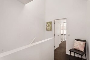 Stylish hallway with a chair and abstract art, leading to a balcony.