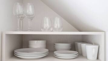 A white shelf with stacked plates and glasses.