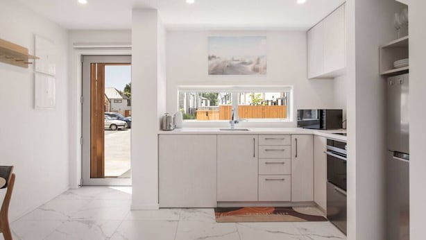 Una cocina moderna con armarios blancos, horno empotrado y refrigerador de acero inoxidable.