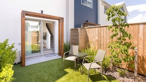 Una casa moderna con un patio, una puerta corrediza de vidrio que da a una escalera y una valla de madera.