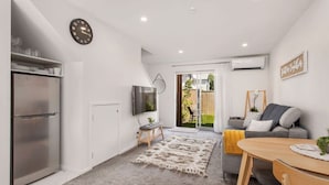 Una cocina moderna con refrigerador empotrado, televisor de pantalla plana y comedor con mesa y sillas de madera.