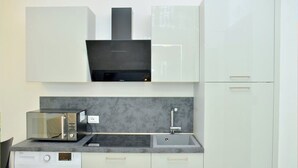 A compact kitchen with a washing machine, microwave, and sink. - Relax Vibes Near the Beach (San Michele al Tagliamento)