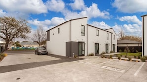 A modern building with a parking area and a car parked in front. - Style Location New Sunny 2Bdrms Free Park (Christchurch)