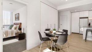 A modern, well-lit room with a dining area, a bed, and a kitchenette.
