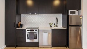 Een moderne keuken met donkere kastjes, een roestvrijstalen koelkast, een magnetron, een oven en een vaatwasser.