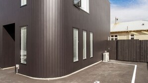 Een modern gebouw met een donkere gevel, grote ramen en een hekpoort.