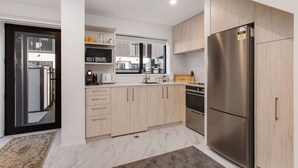 Une cuisine moderne avec des meubles en bois clair, des appareils en acier inoxydable et un grand réfrigérateur.