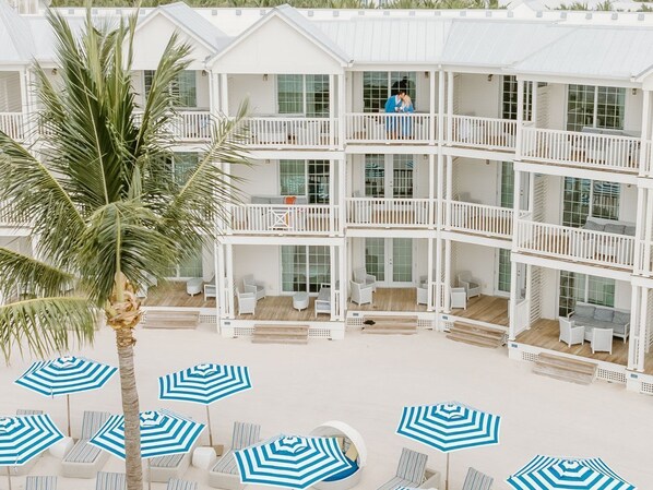 A multi-story hotel with balconies, outdoor seating areas, and palm trees. - Marathon Oceanfront Suite | Balcony + 2 Luxe Baths (Marathon)