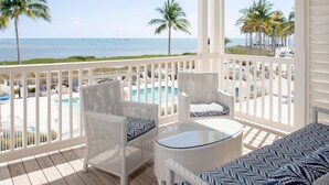 A covered outdoor area with a pool, white wicker furniture, and a view of the ocean and beach. - Marathon Oceanfront | 2 King Beds + Balcony (Marathon)
