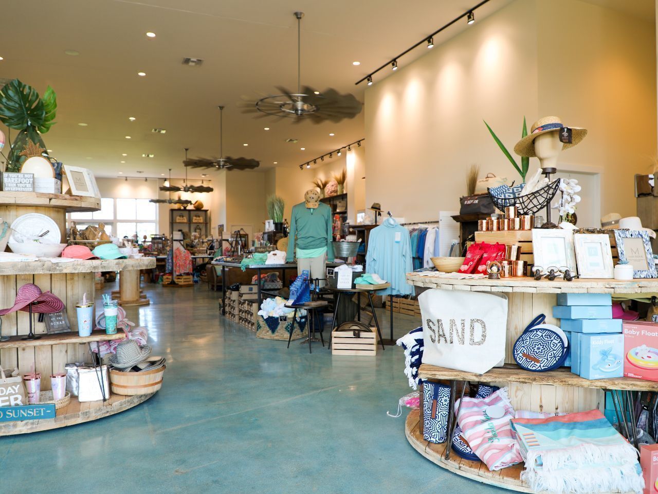 A spacious boutique store with wooden display shelves and a mannequin dressed in a green top.