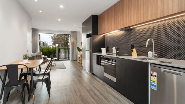 A modern kitchen with a central island, stainless steel appliances, and a black hexagonal backsplash.