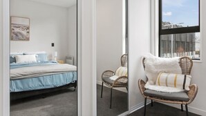 A bedroom with a bed, a chair, a mirror, and a window.