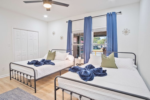 A room with two beds, a ceiling fan, a window with curtains, and a door. - Perfect Spot to Relax 4BR 3BA Near Dtown Hemisfair (San Antonio)