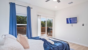 Une chambre à coucher avec un lit, des rideaux, une télévision et un balcon.