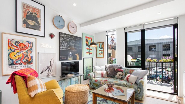A modern living room with a sofa, armchair, and coffee table, a flat-screen TV, and various artworks on the walls. - Best location in CBD, Carpark (Christchurch)