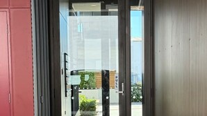 A modern building entrance with a glass door, a pull handle, and a concrete floor.
