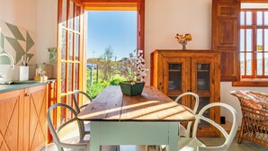 A wooden dining table with chairs, a potted plant, and a view of the outdoors.