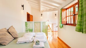 A hotel room with a bed, towels, a wooden door, and a window with curtains.
