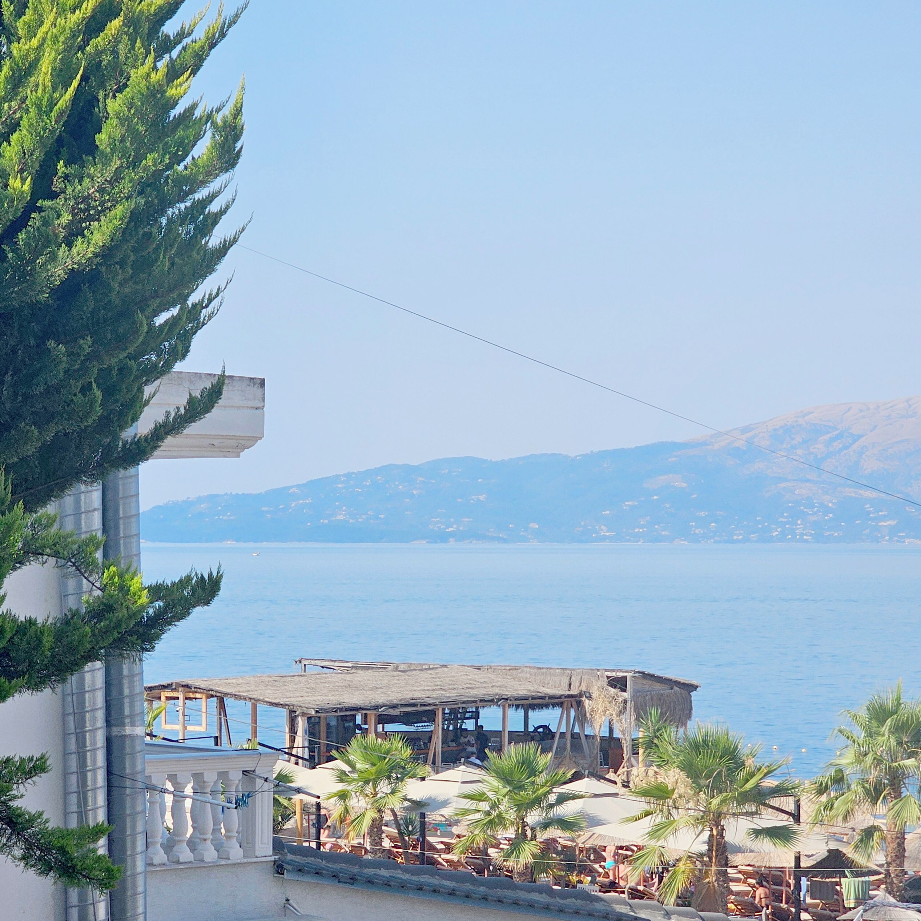Une vue sur la mer avec un bâtiment doté d’un balcon et d’un espace extérieur aménagé pour s’asseoir.
