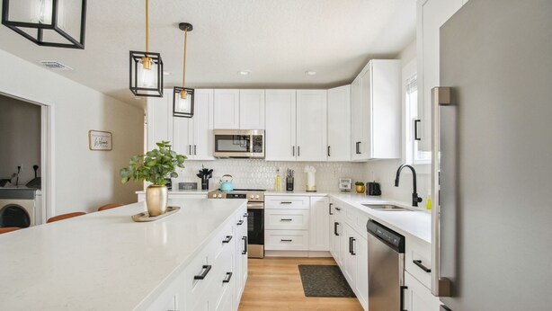 A modern kitchen with white cabinetry, a central island, a built-in microwave, and a dishwasher. - Stylish Spacious Comfort 4BR 3BA Downtown Gem (San Antonio)