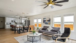 A spacious living area with a dining table, sofa, and chairs, a ceiling fan, and large windows. - Stylish Spacious Comfort 4BR 3BA Downtown Gem (San Antonio)