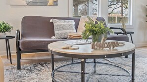 A modern living room with a round metal table, a sofa, and a potted plant. - Stylish Spacious Comfort 4BR 3BA Downtown Gem (San Antonio)