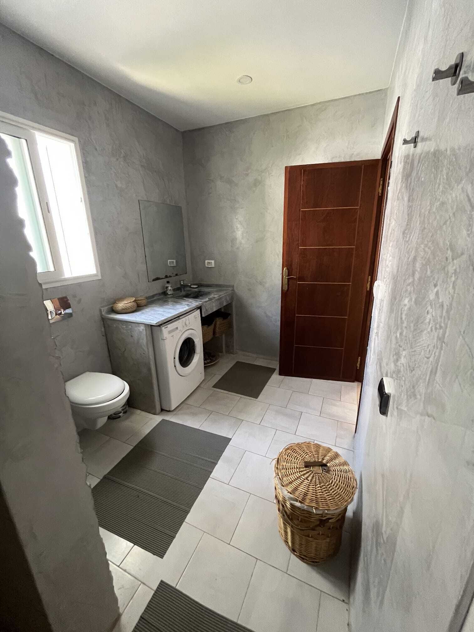 Une petite salle de bain comprenant des toilettes, un lave-linge et un lavabo.