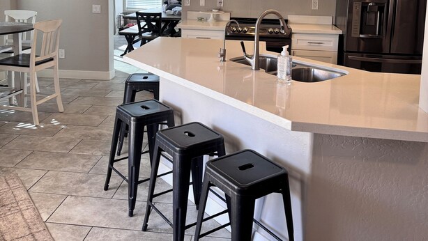 Une cuisine moderne dotée d’un îlot central, d’appareils électroménagers en acier inoxydable et d’un coin repas avec des tabourets de bar.