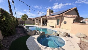 Un jardin avec une piscine, un jacuzzi et un espace patio.