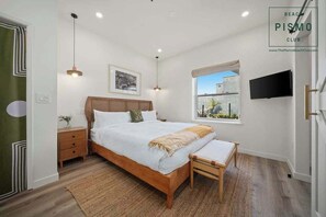 Un dormitorio con cama, mesitas de noche, televisor y ventana con vistas.
