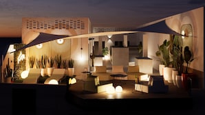 An outdoor lounge area with seating, potted plants, and a modern architectural design. - Sholeo Lodges Las Canteras Flats (Las Palmas de Gran Canaria)