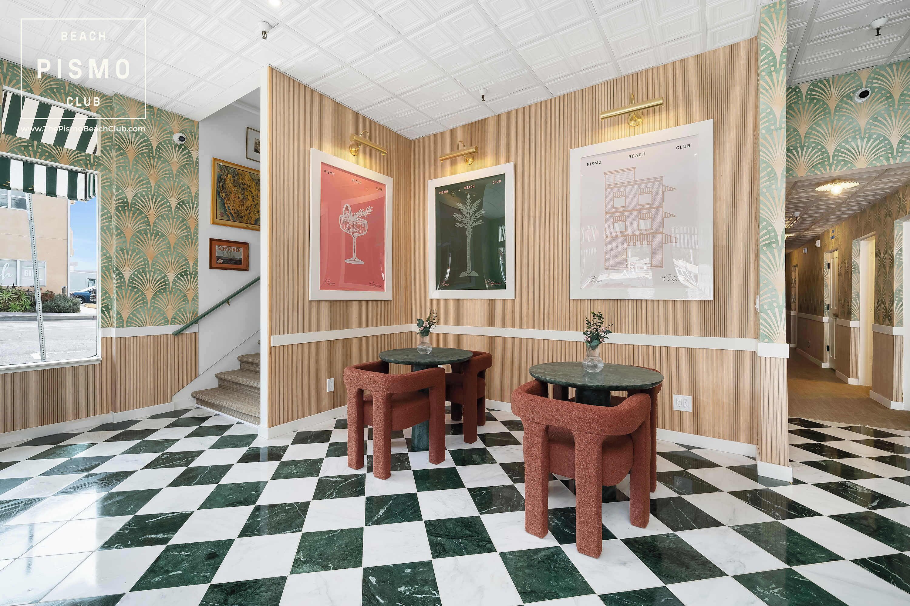 Eine Hotelhalle mit Schachbrettparkett, Holzvertäfelung und gerahmten Kunstwerken an den Wänden.