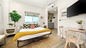 Une chambre moderne avec un lit, des tables de chevet, une télévision et une vue sur la plage.