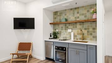 Eine Küche mit Geschirrspüler, Backofen und einem an der Wand befestigten Fernseher.