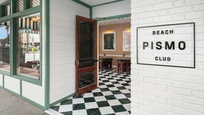 Une entrée d’immeuble avec un sol à carreaux, une porte et une enseigne indiquant « BEACH PISMO CLUB ».