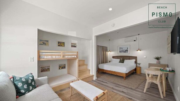 Une chambre d’hôtel comprenant un lit, un canapé, un banc, une petite table et un escalier menant à une autre pièce.