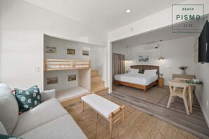 Une chambre d’hôtel comprenant un lit, un canapé, un banc, une petite table et un escalier menant à une autre pièce.