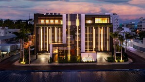 A modern hotel with a glass facade, a prominent entrance, and a landscaped front yard.