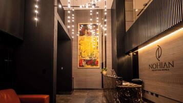 Een hotel receptie met een modern design, met een receptiebalie, een groot abstract schilderij en een zithoek met een rode bank.
