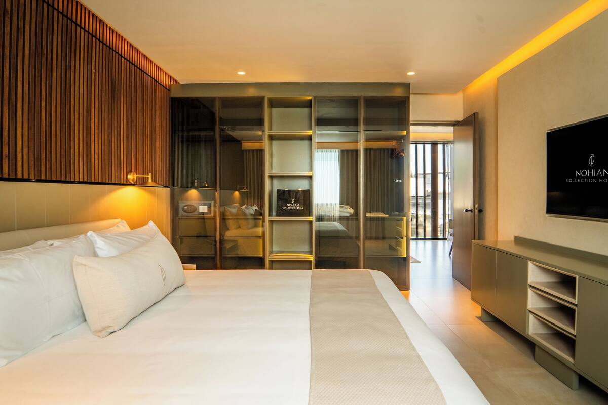 A modern hotel room with a large bed, a television, and a view of the city.