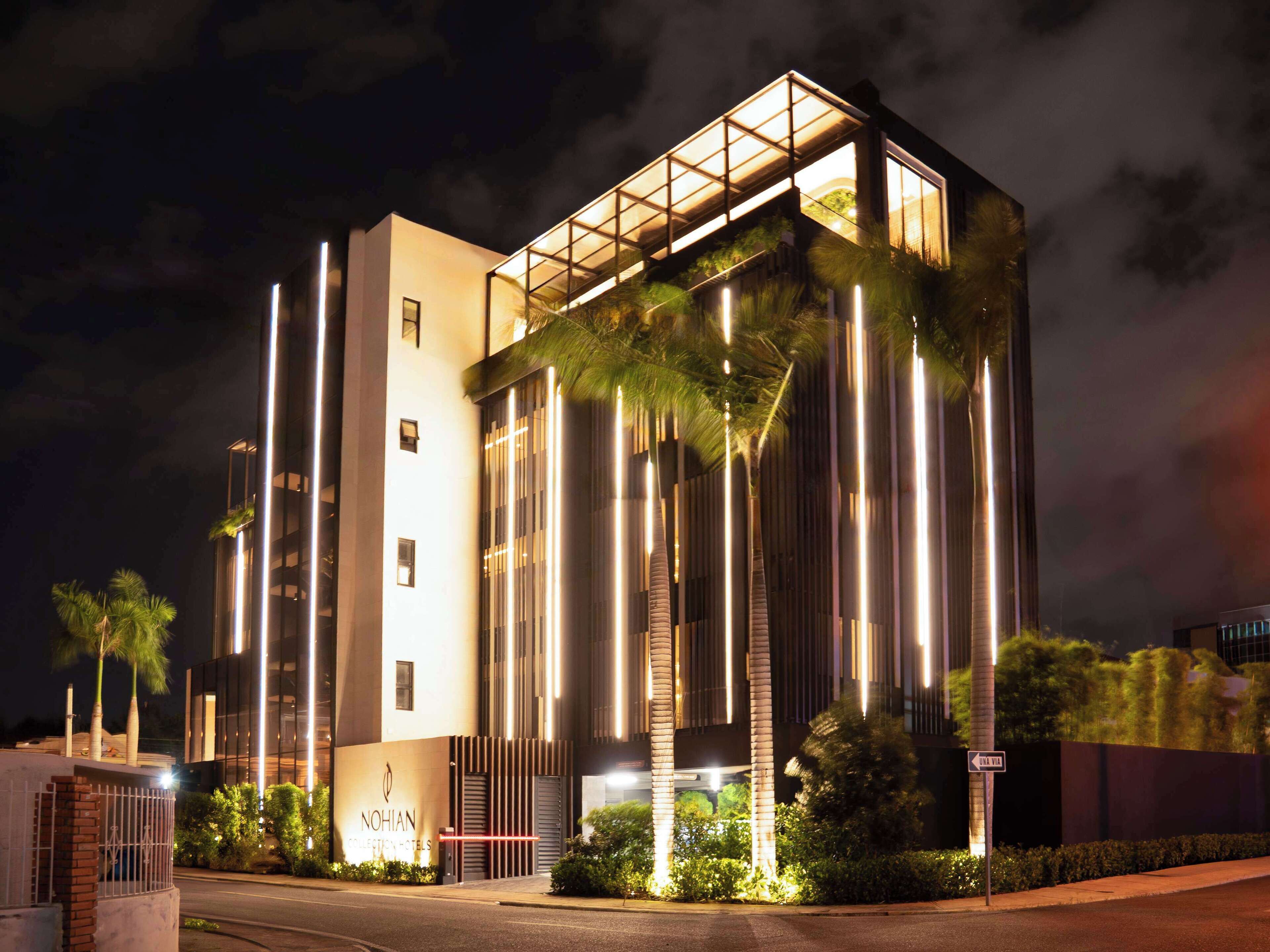 A modern hotel with a glass facade, a prominent entrance, and a well-lit exterior.