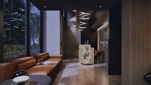 A modern reception area with a marble reception desk, leather seating, and a large window offering a view of the outdoors.