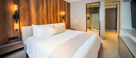 A modern hotel room with a large bed, wooden panel wall, and a mirror.