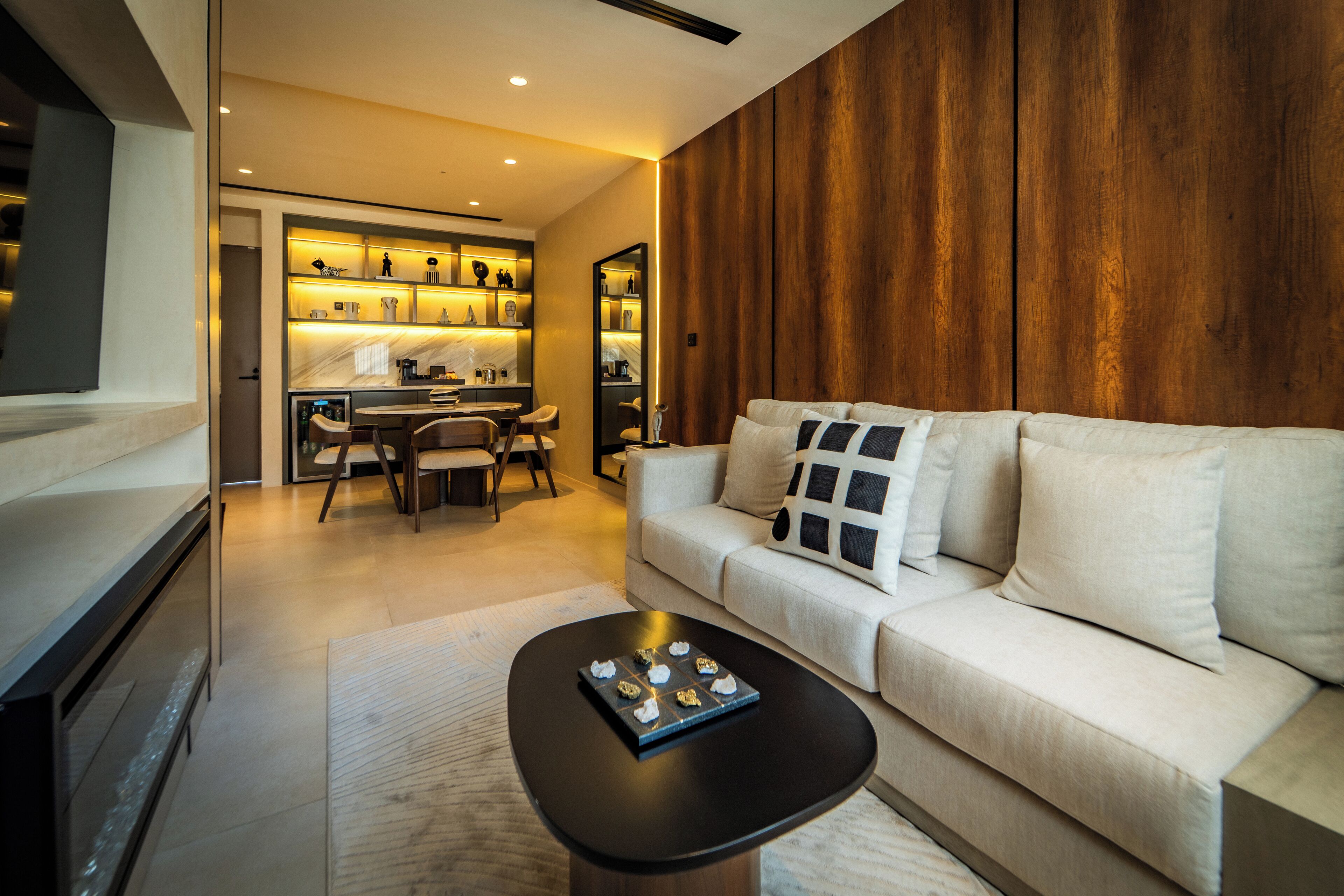 A modern living room with a sofa, coffee table, and a kitchen area in the background.
