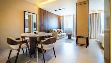 A modern hotel room with a dining area, a sofa, and a bed.
