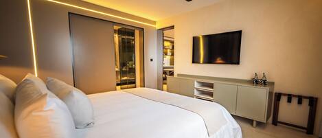 Un dormitorio moderno con una cama grande, un armario, un televisor montado en la pared y un vestidor.