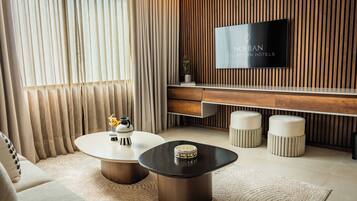 A modern living room with a flat-screen TV, a round coffee table, a sofa, and a wooden accent wall.
