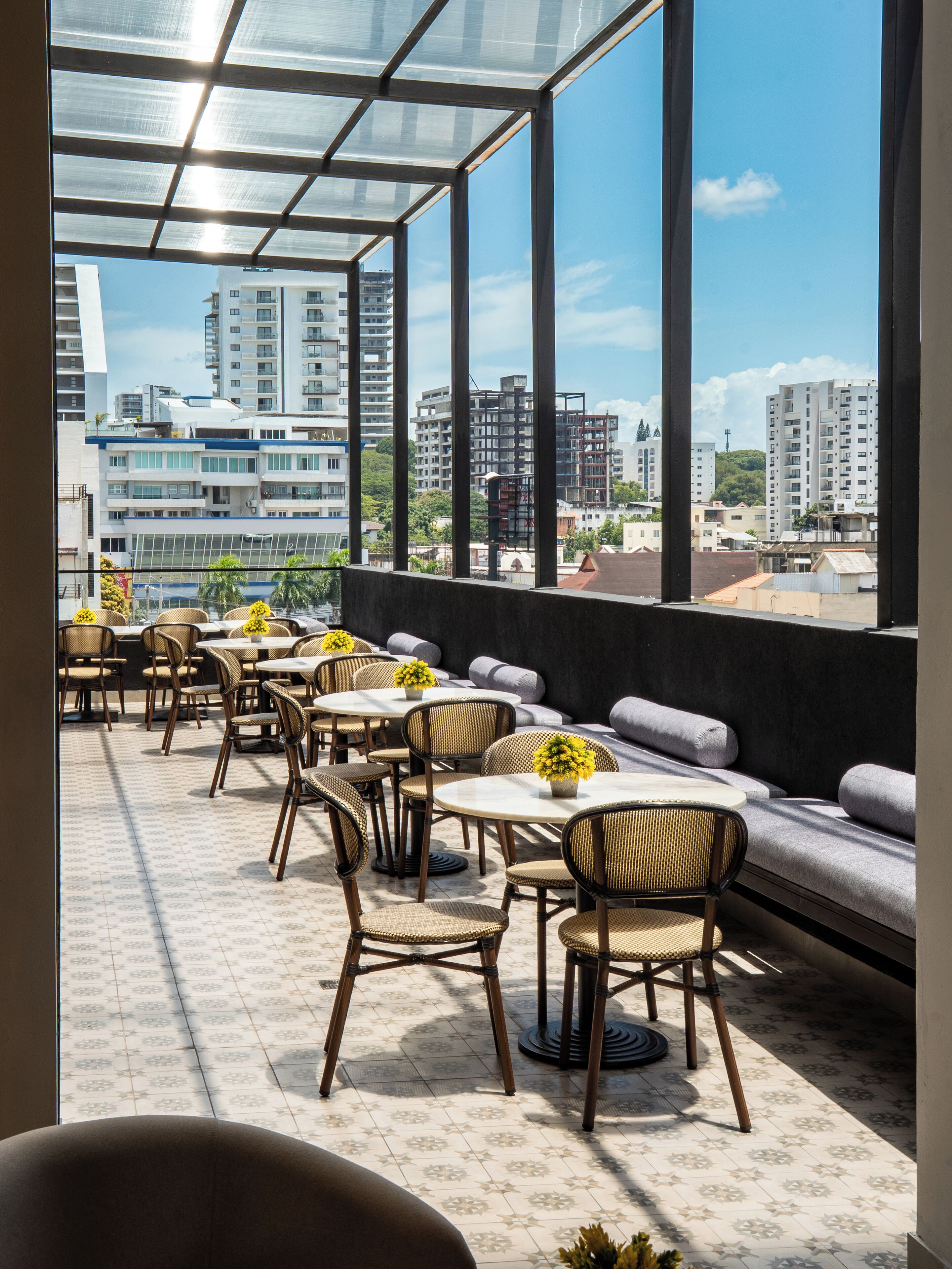 A rooftop terrace with outdoor seating, a view of the cityscape, and a modern architectural design.