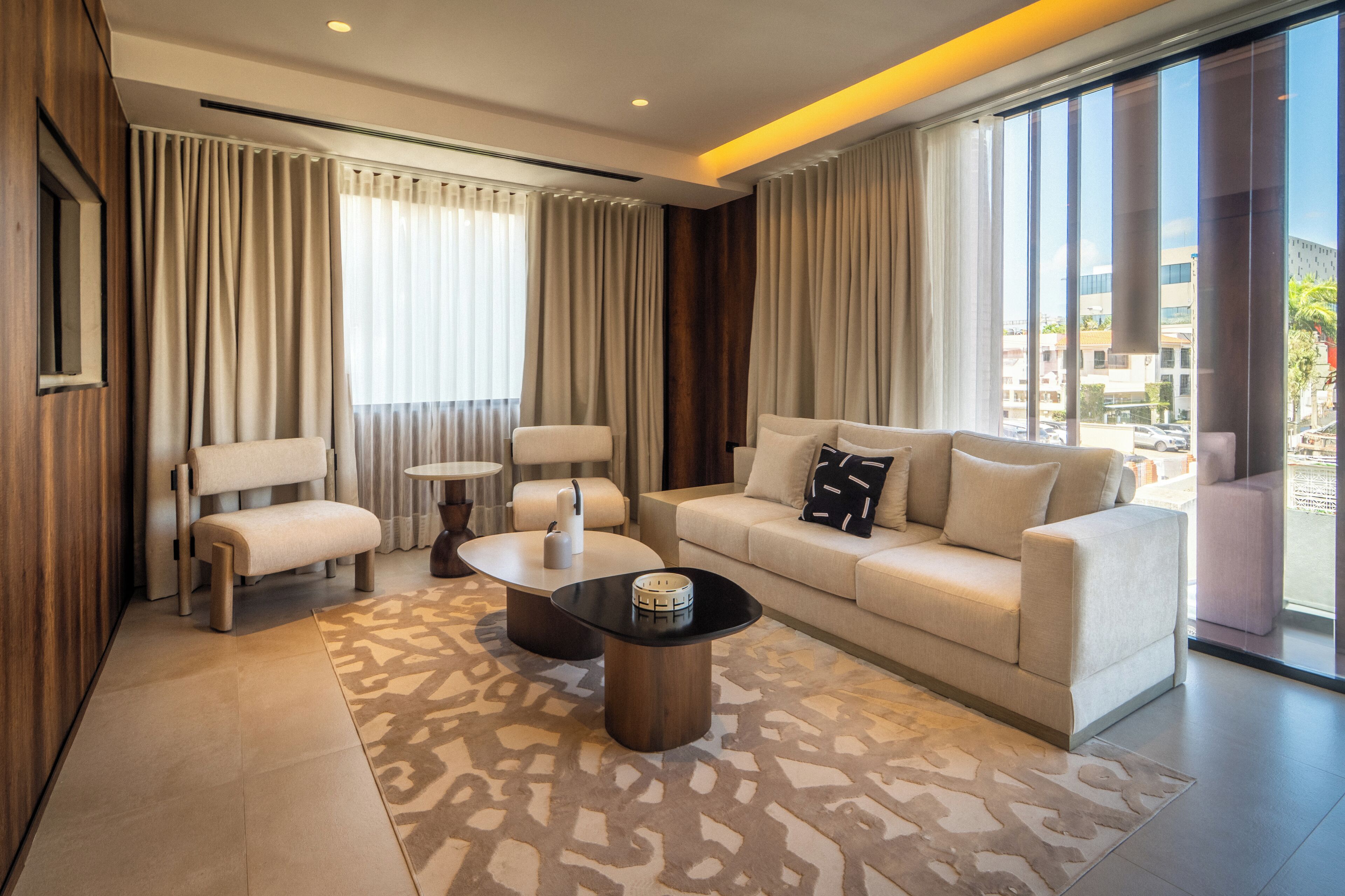 A modern living room with a sofa, two armchairs, a coffee table, and a patterned rug.